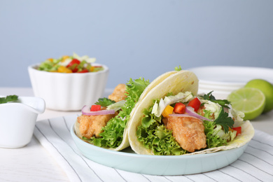 Photo of Yummy fish tacos served on white table