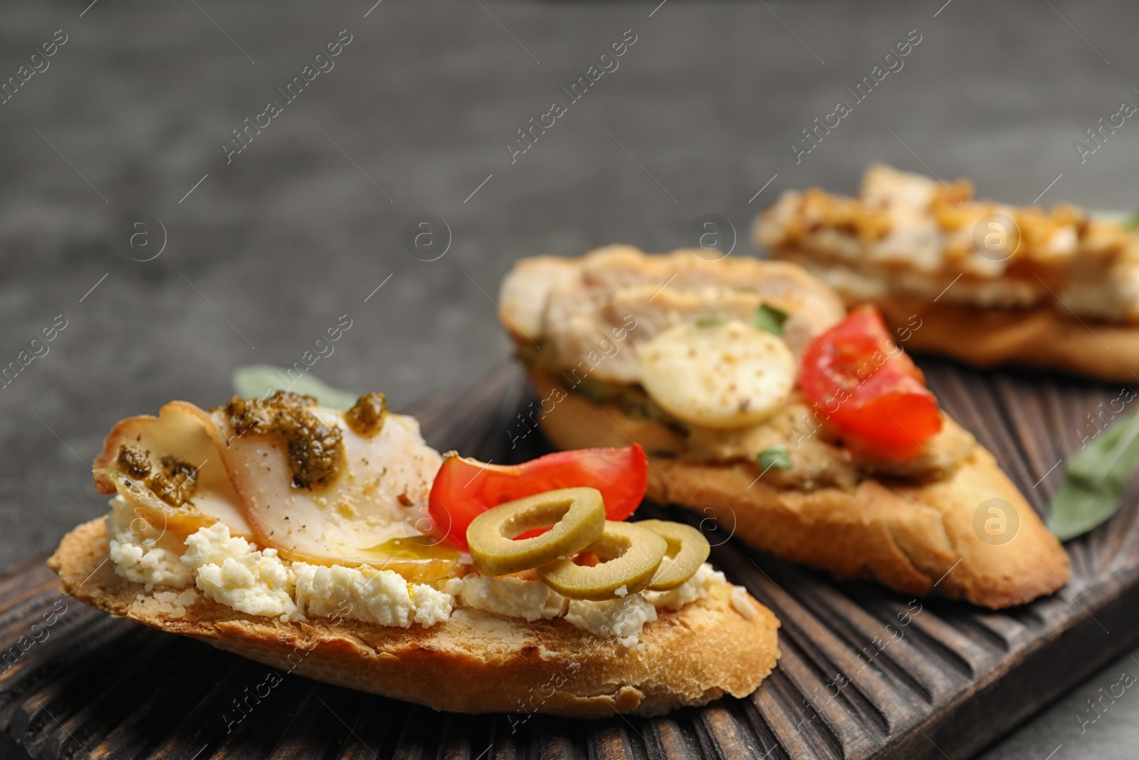 Photo of Board with delicious chicken bruschettas on table, closeup