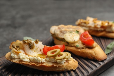 Board with delicious chicken bruschettas on table, closeup