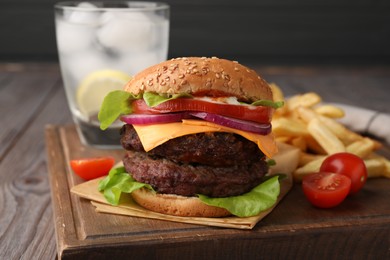 Photo of Tasty cheeseburger with patties, French fries and tomatoes on wooden table, closeup