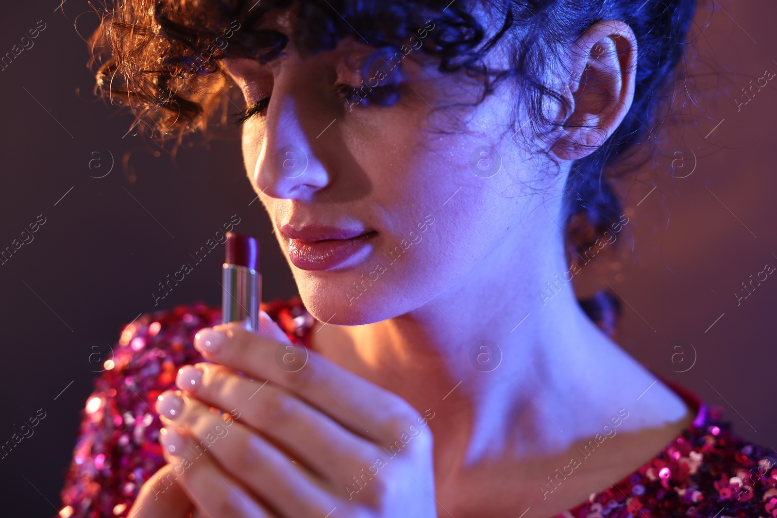 Photo of Beautiful young woman with lipstick posing on color background in neon lights