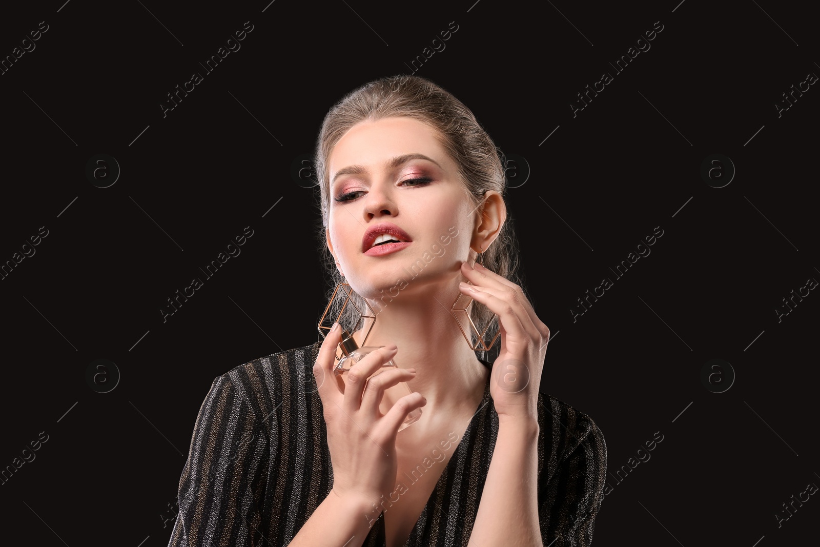 Photo of Beautiful young woman with bottle of perfume on black background