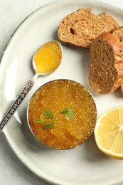 Photo of Fresh pike caviar in bowl, lemon and bread on light table, top view