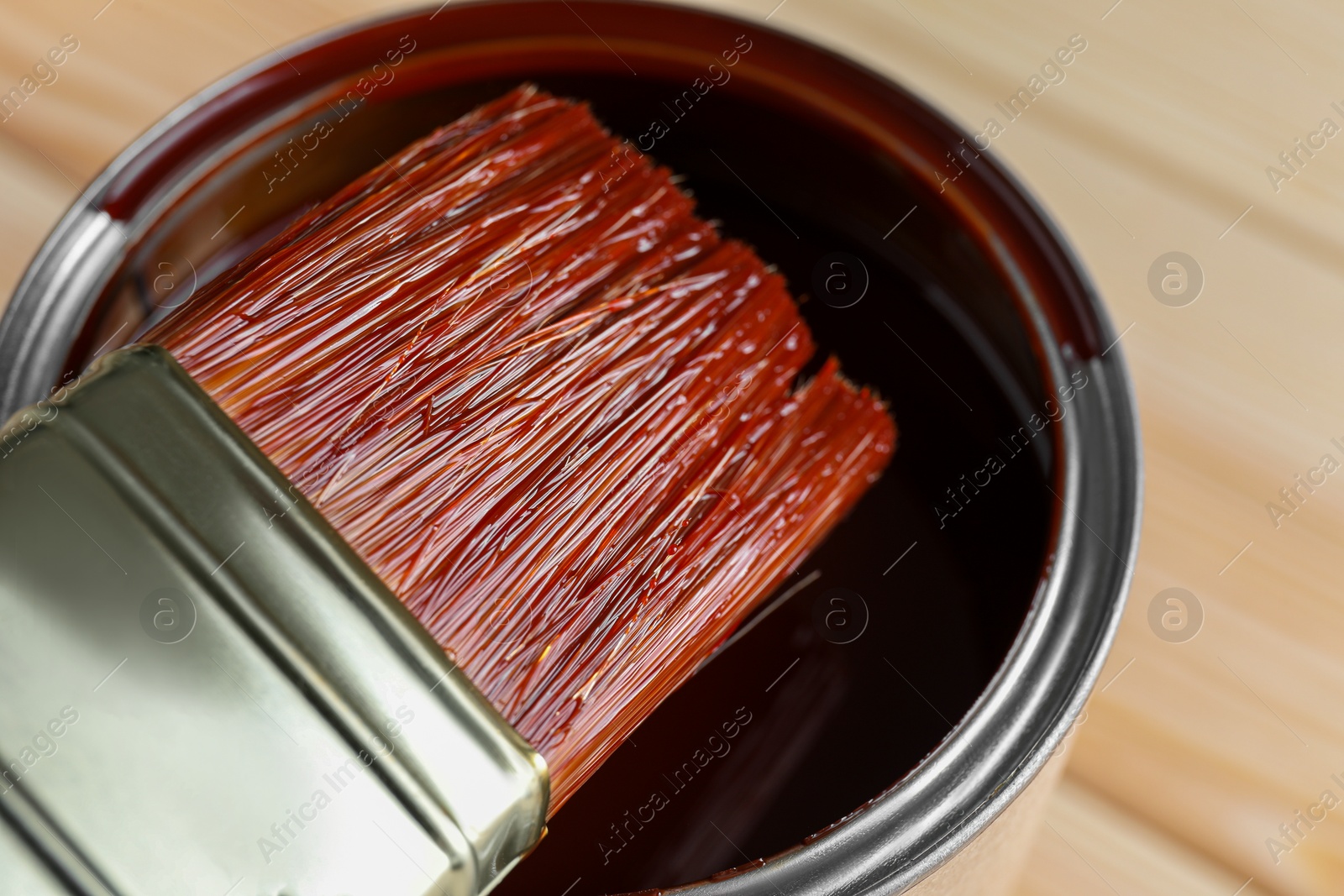 Photo of Brush with wood stain over can on table, closeup