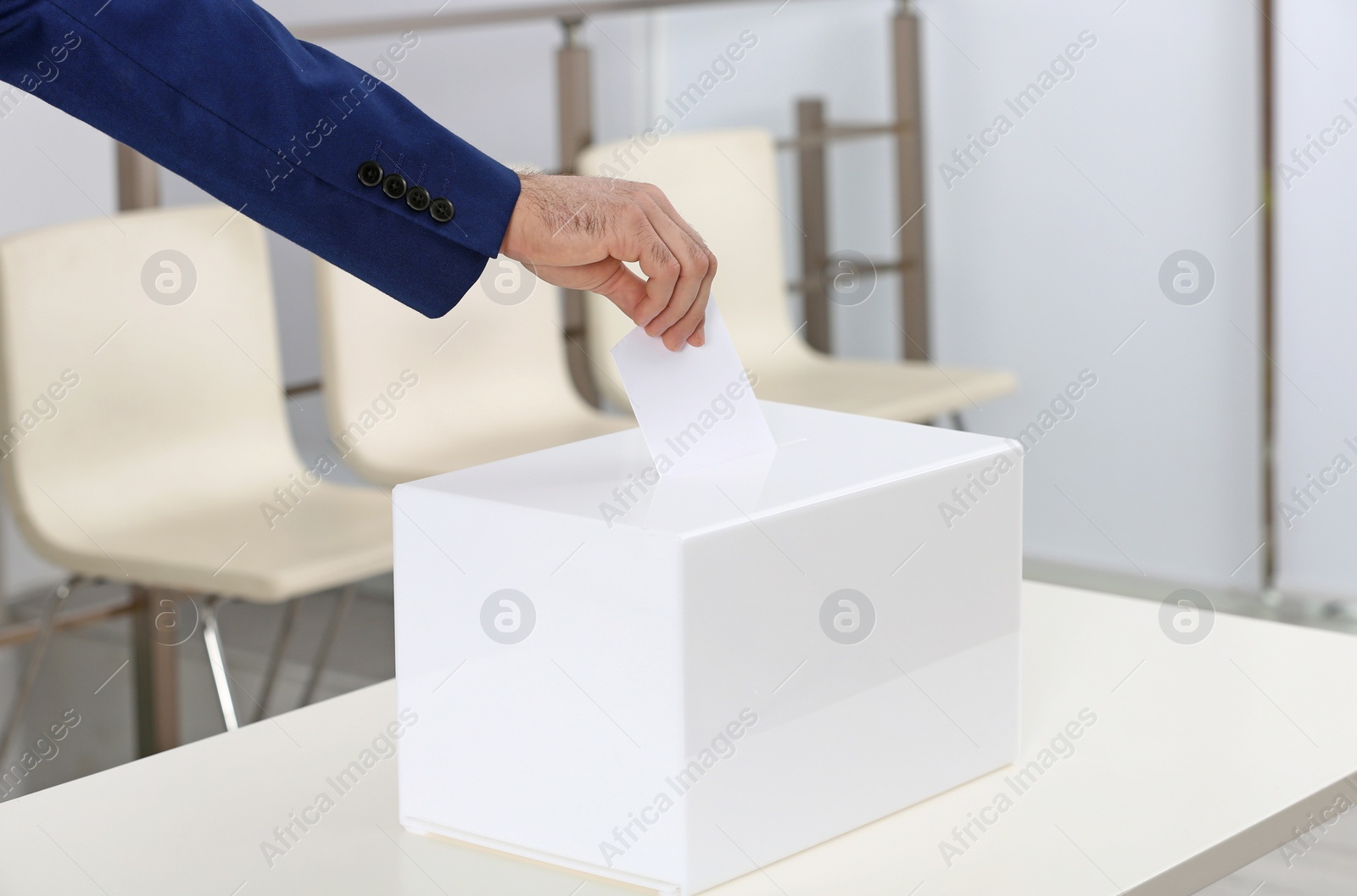 Photo of Man putting his vote into ballot box at polling station, closeup