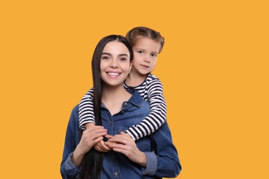 Photo of Happy woman with her cute daughter on yellow background. Mother's day celebration
