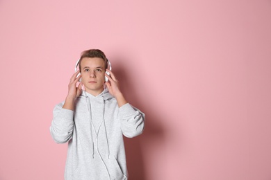 Teen boy listening to music with headphones on color background, space for text