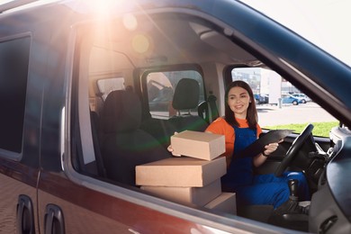 Courier with clipboard checking packages in car