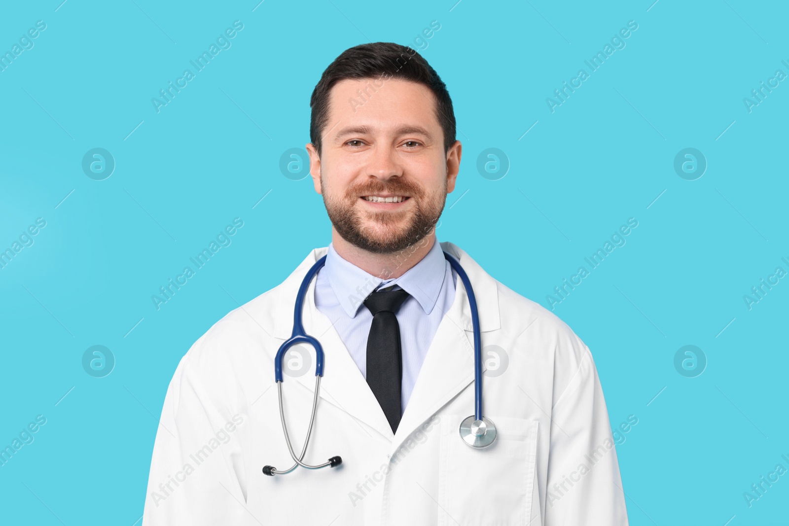 Photo of Smiling doctor with stethoscope on light blue background