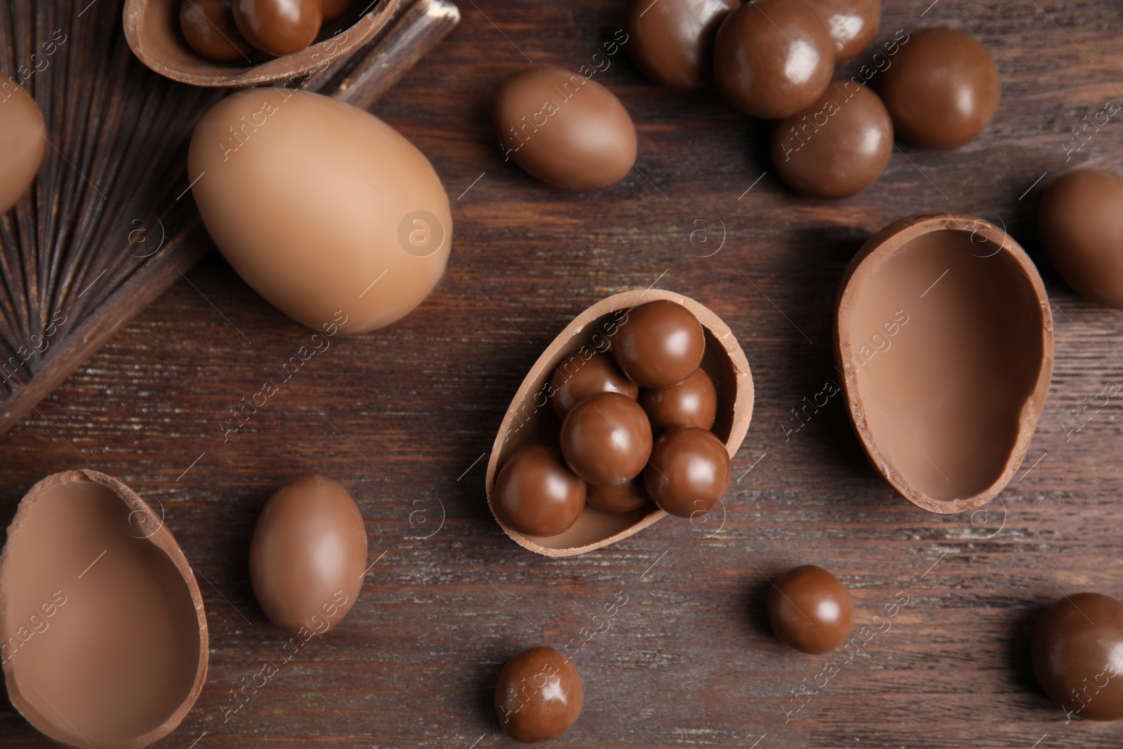 Photo of Tasty chocolate eggs and candies on wooden table, flat lay