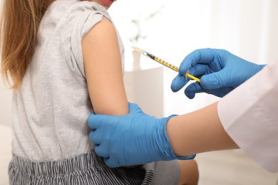 Photo of Doctor giving injection to little girl in hospital, closeup. Immunization concept