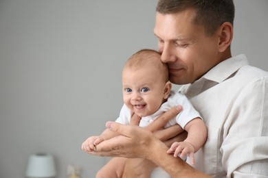 Happy father holding his cute baby at home, space for text