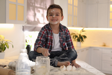 Cute little boy with flour on face in kitchen. Cooking dough