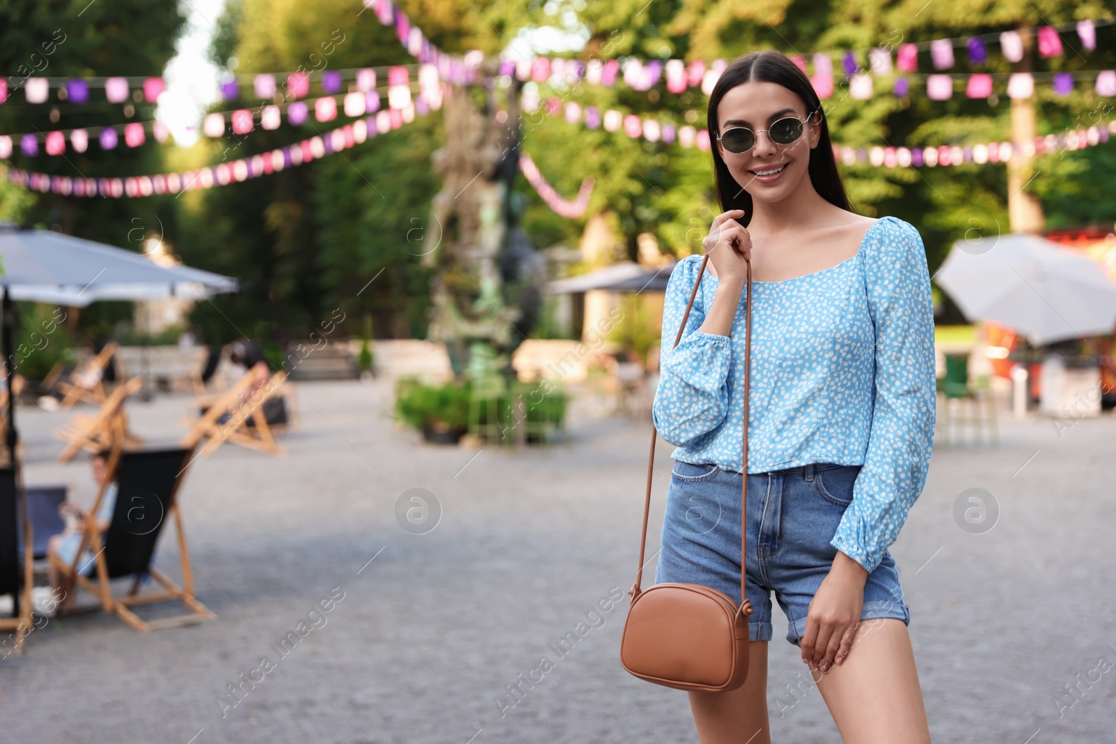 Photo of Young woman with stylish bag outdoors, space for text