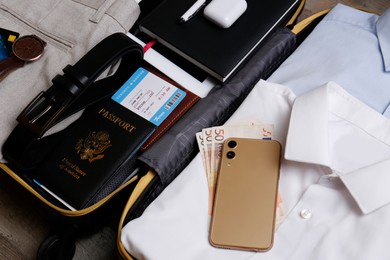 Photo of Packed suitcase with business trip stuff on wooden surface