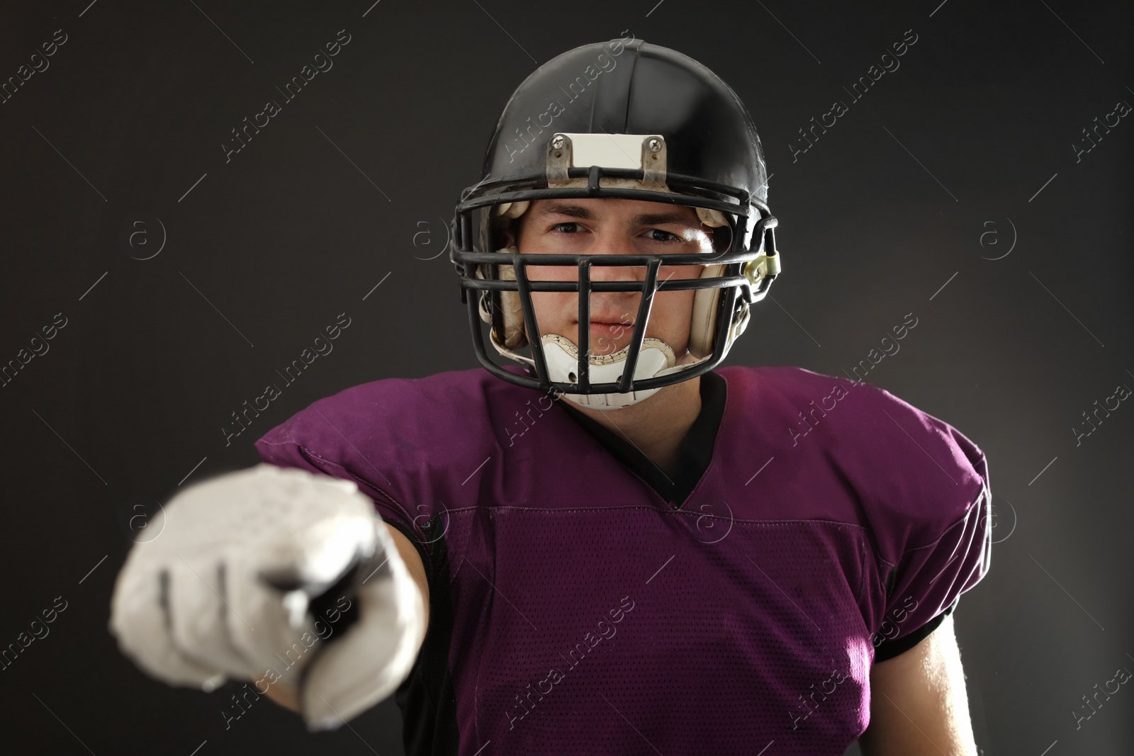 Photo of American football player wearing uniform on dark background