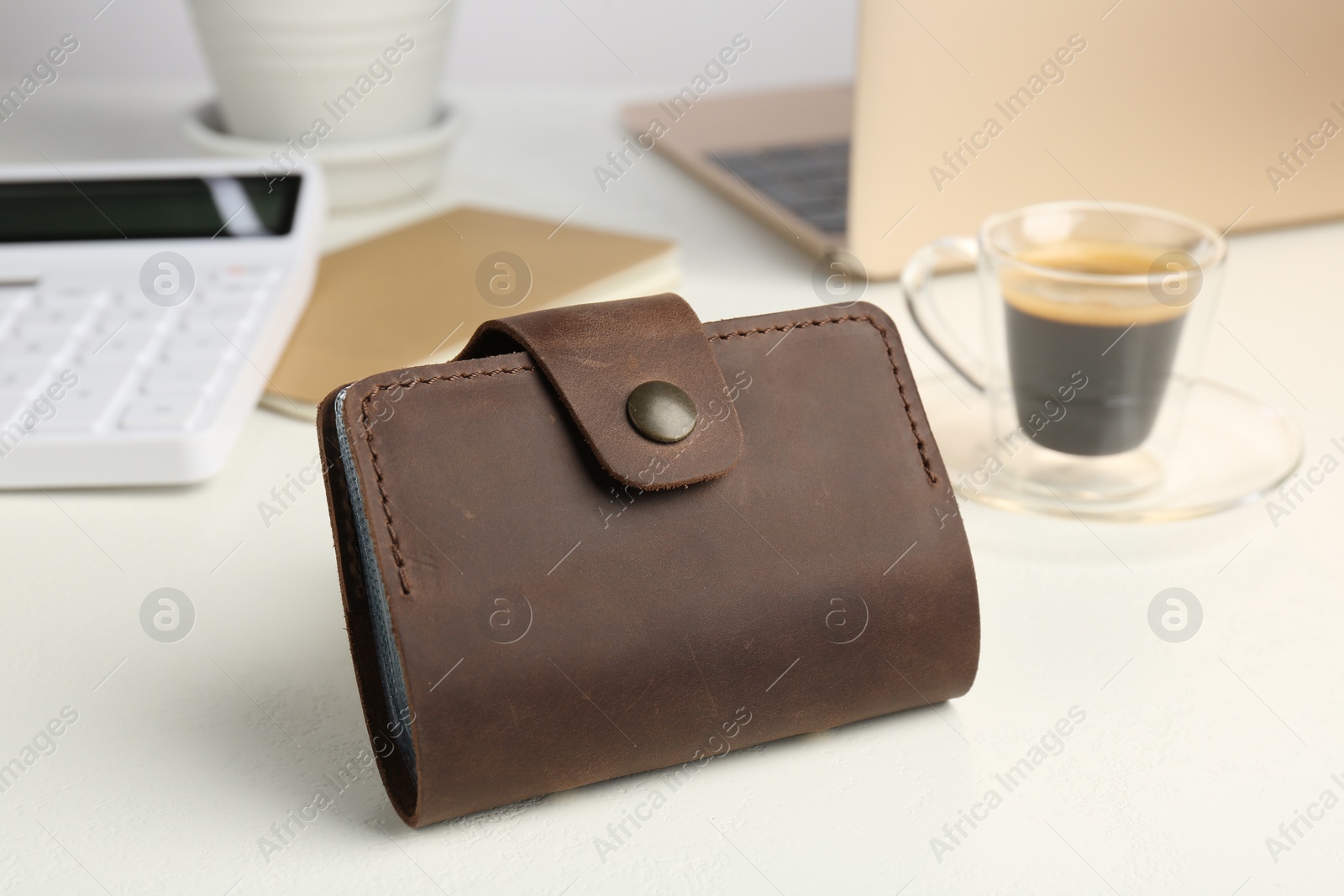 Photo of Leather card holder, calculator and coffee on white table