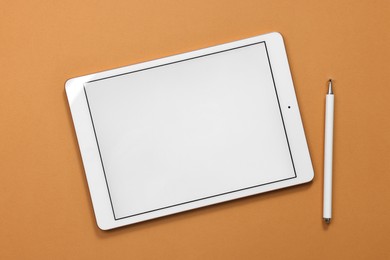 Photo of Modern tablet and stylus on orange background, flat lay. Space for text