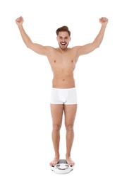 Fit man standing on bathroom scale against white background. Weight loss