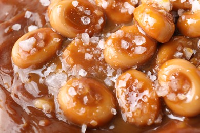 Tasty candies, caramel sauce and salt as background, top view