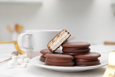 Photo of Saucer with delicious choco pies and cup of drink on white table indoors, closeup
