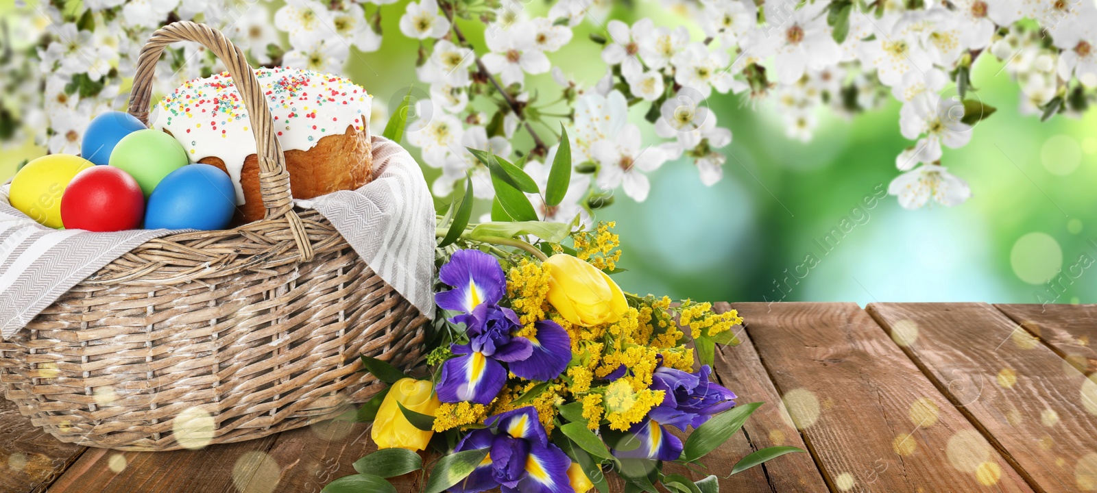 Image of Basket with traditional Easter cake, eggs and flowers on wooden table outdoors, space for text. Banner design