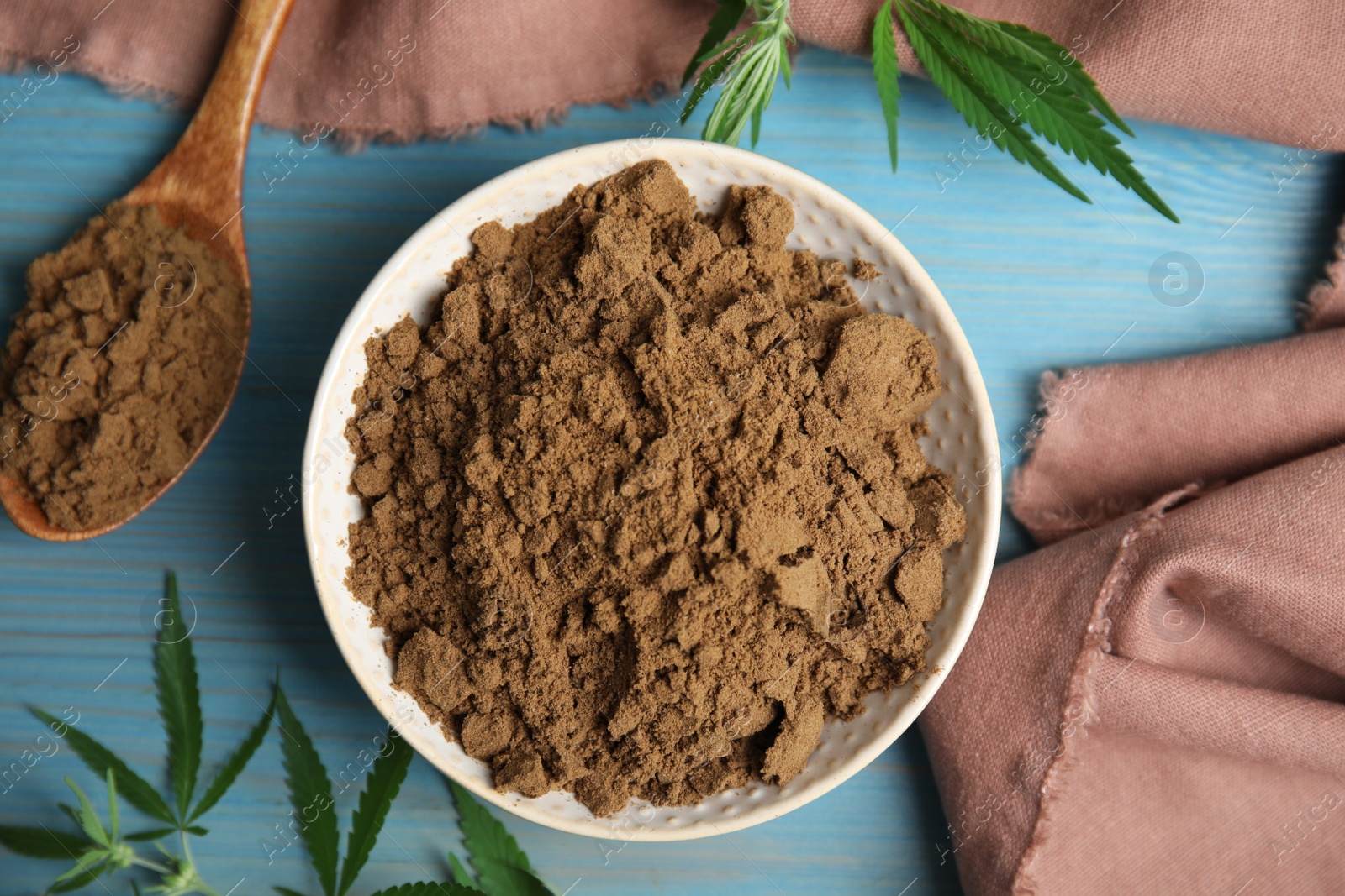 Photo of Hemp protein powder and fresh leaves on light blue wooden table, flat lay