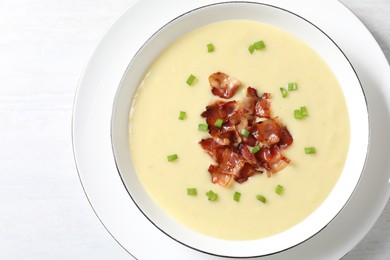 Photo of Tasty potato soup with bacon and green onion in bowl on white table, top view