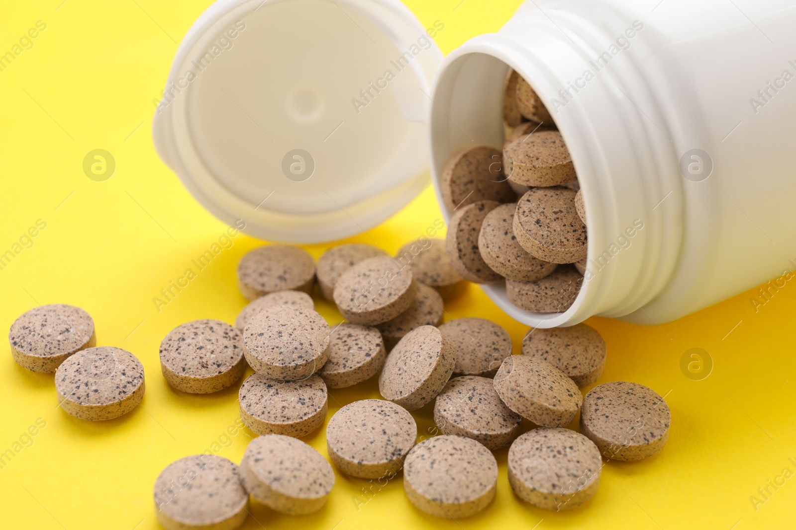 Photo of Medical bottle with beer yeast pills on yellow background, closeup