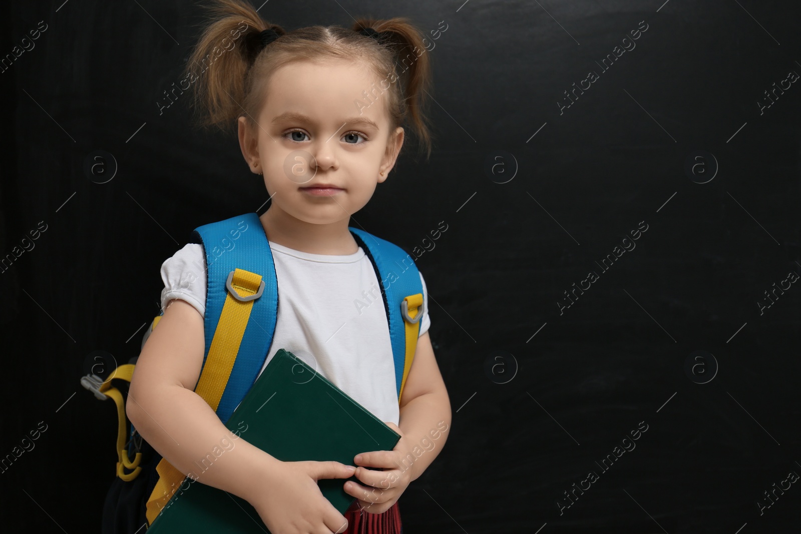 Photo of Cute little child near chalkboard, space for text. First time at school