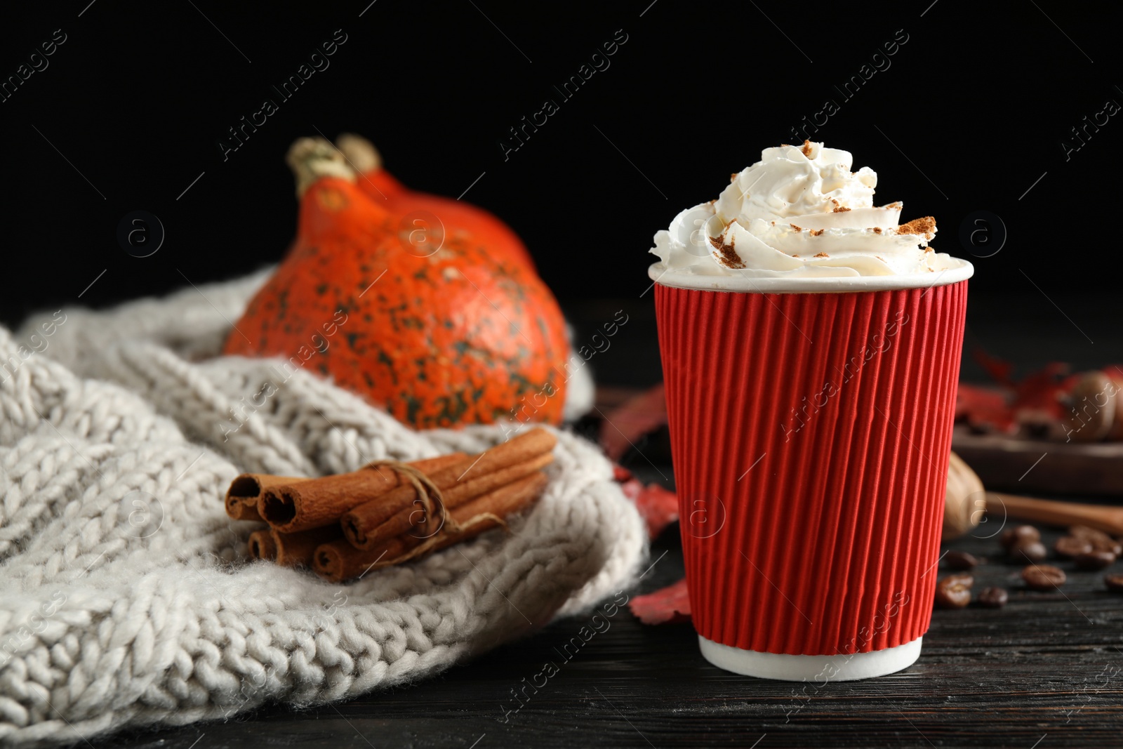 Photo of Paper cup with tasty pumpkin spice latte on black wooden table