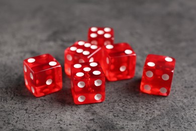 Photo of Many red game dices on grey textured table, closeup