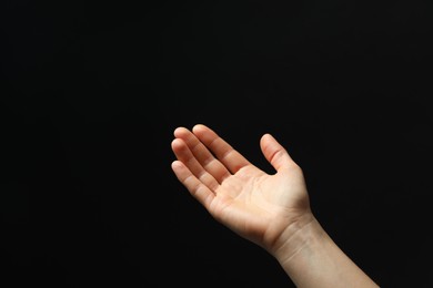 Photo of Woman holding something in hand on black background, closeup. Space for text