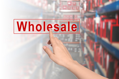 Image of Woman clicking Wholesale button and blurred view of warehouse on background 