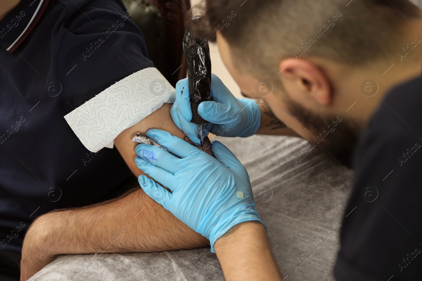 Photo of Professional tattoo master working with client in salon