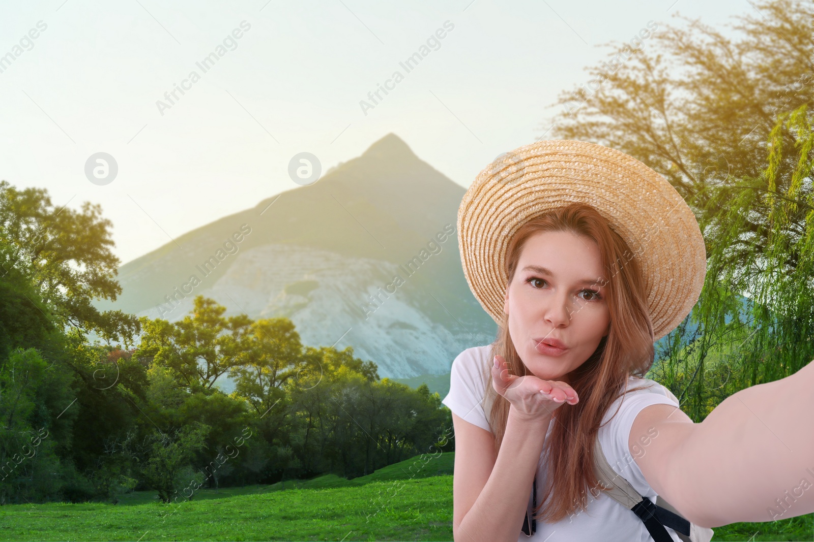 Image of Beautiful woman in straw hat taking selfie in mountains