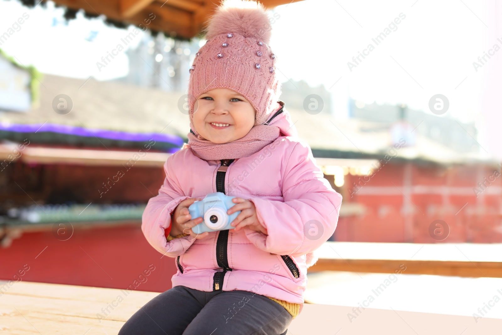 Photo of Cute little photographer with toy camera outdoors