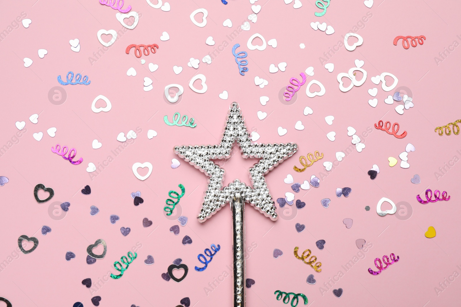 Photo of Beautiful silver magic wand and confetti on pink background, flat lay