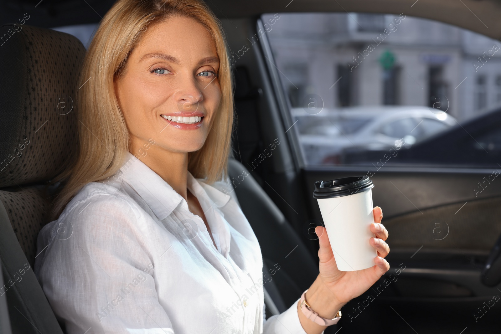 Photo of Coffee to go. Happy woman with paper cup of drink in car