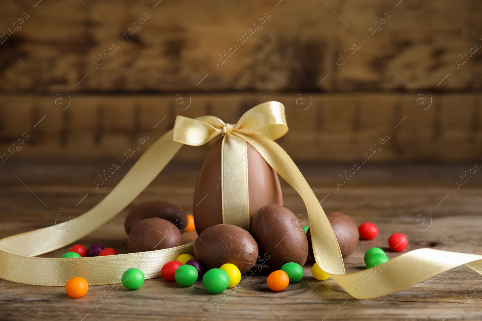 Photo of Tasty chocolate eggs and colorful candies on wooden table