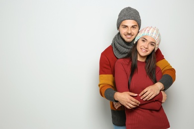 Young happy couple in warm clothes on light background. Christmas celebration