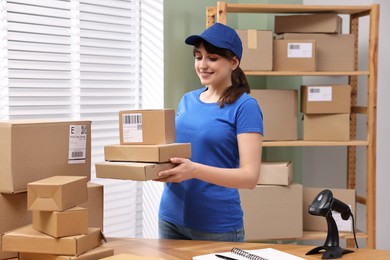 Photo of Parcel packing. Post office worker with parcels at wooden table indoors