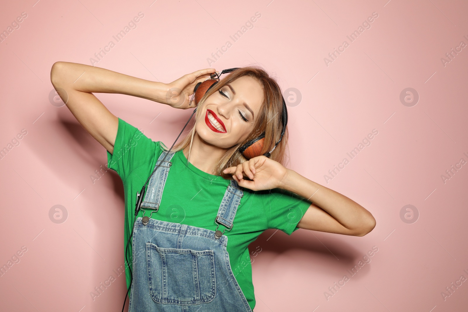 Photo of Beautiful young woman with healthy long blonde hair and headphones on color background