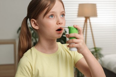 Photo of Little girl using throat spray at home