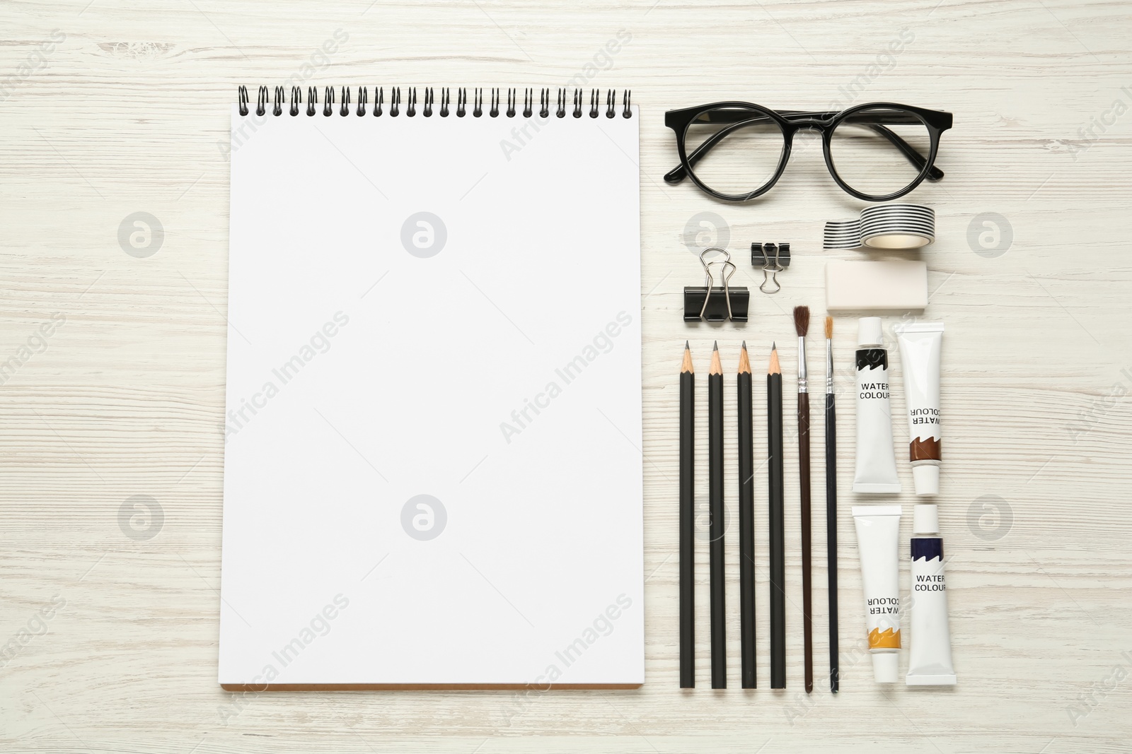 Photo of Flat lay composition with blank sketchbook on white wooden table. Space for text
