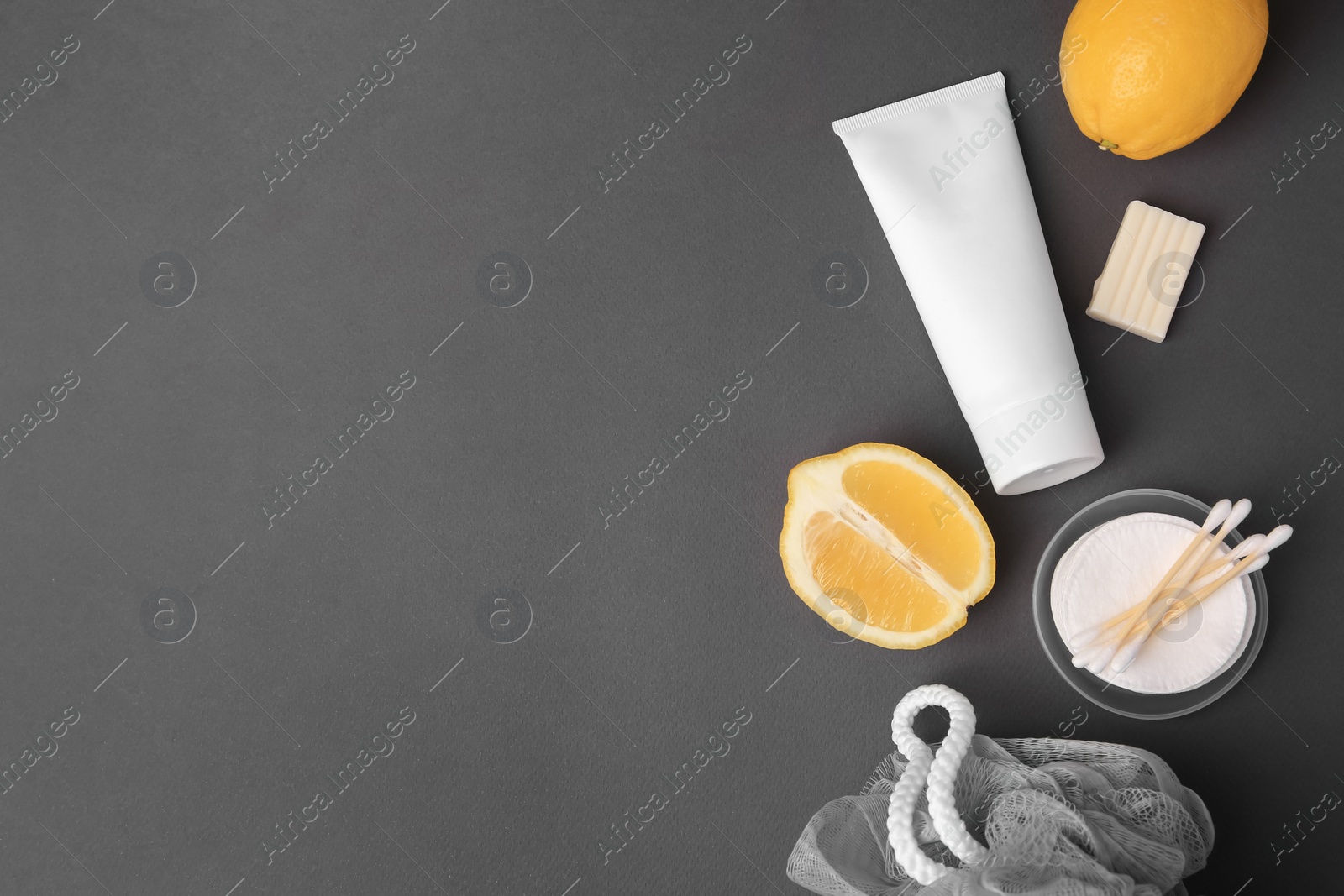 Photo of Lemon face wash. Fresh citrus fruits and personal care products on dark grey background, flat lay. Space for text