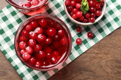 Photo of Tasty cranberry juice in glasses and fresh berries on wooden table, flat lay