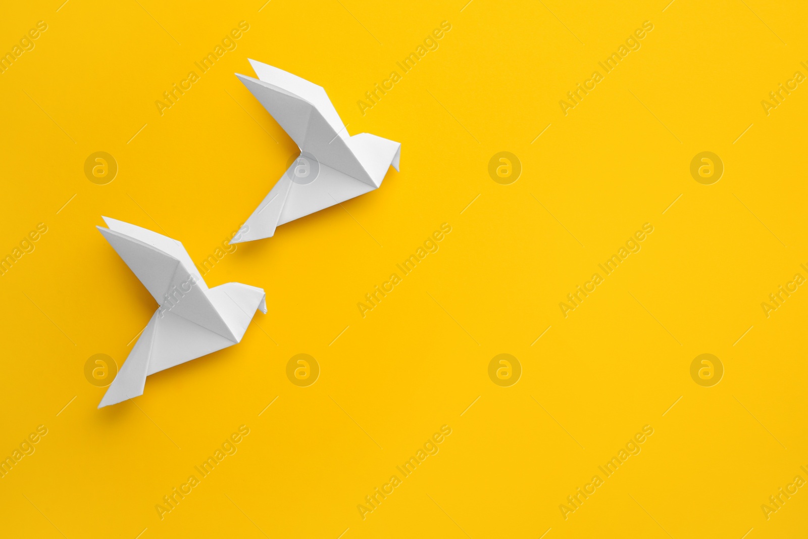 Photo of Origami art. Colorful handmade paper birds on yellow background, flat lay. Space for text