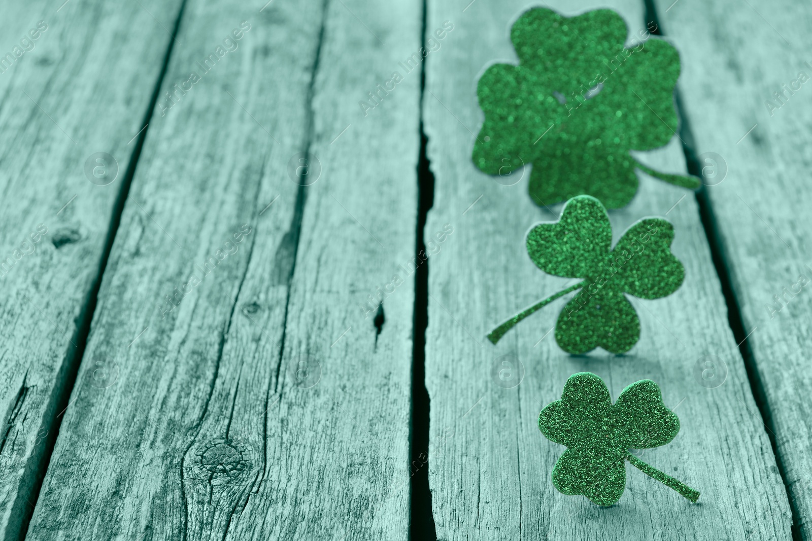 Image of St. Patrick's day. Decorative clover leaves on green wooden background, space for text