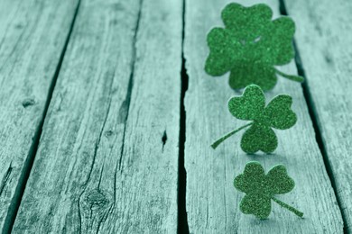 Image of St. Patrick's day. Decorative clover leaves on green wooden background, space for text